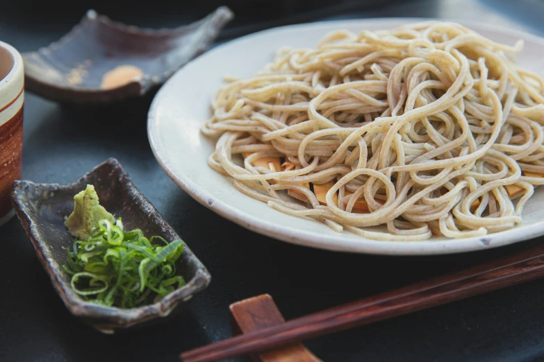 a plate of noodles and chopsticks on a table, unsplash, mingei, close up of lain iwakura, grain”