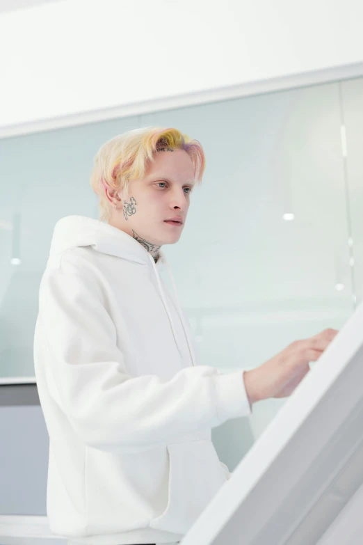 a man in a white hoodie standing in front of a computer, inspired by Lasar Segall, featured on reddit, albino hair, yung lean, wearing a light - pink suit, playing piano