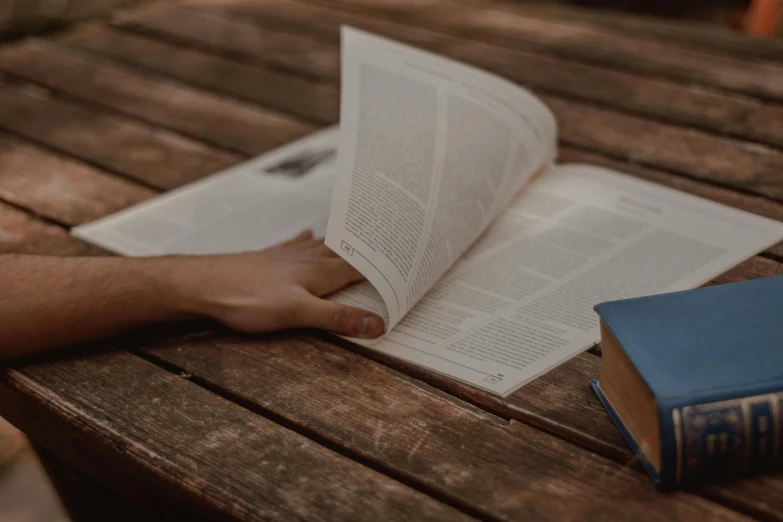 a person reading a book on a wooden table, by Carey Morris, pexels contest winner, happening, full page periodical image, biblical image, background image, schools
