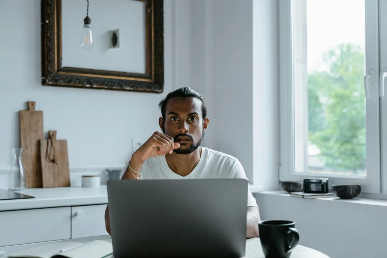 a man sitting in front of a laptop computer, pexels contest winner, mixed race, serious composure, avatar image, vinayak