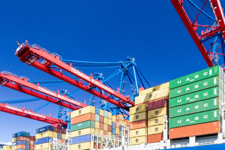 a large container ship sitting on top of a body of water, inspect in inventory image, view from ground level, vibrant colour, cranes