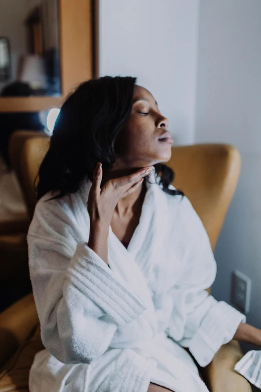 a woman in a bathrobe sitting in a chair, by Carey Morris, pexels, focused on her neck, pleasing, african american woman, stressing out