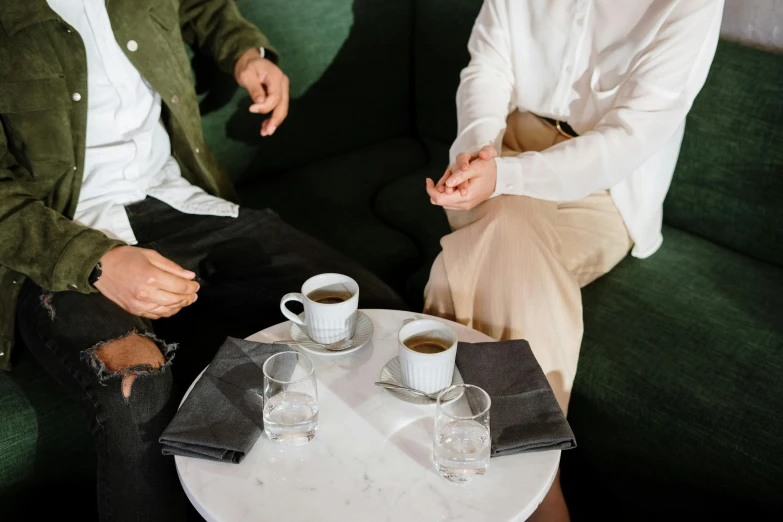 a couple of men sitting on top of a green couch, trending on unsplash, private press, coffee stain on napkin, aussie baristas, in meeting together, white tablecloth