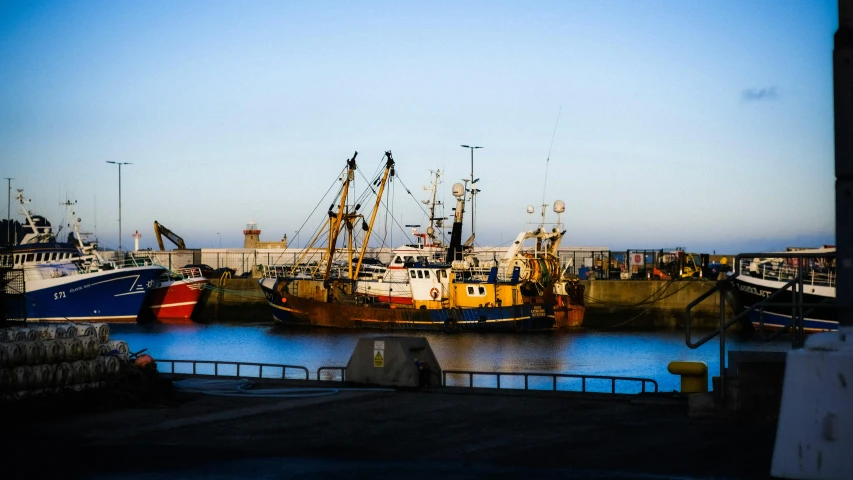 a number of boats in a body of water, by Andries Stock, pexels contest winner, maryport, big graphic seiner ship, evening time, docked at harbor