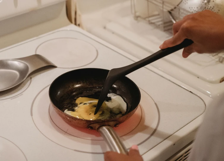 a person cooking eggs in a frying pan on a stove, by Carey Morris, fan favorite, using fork, image