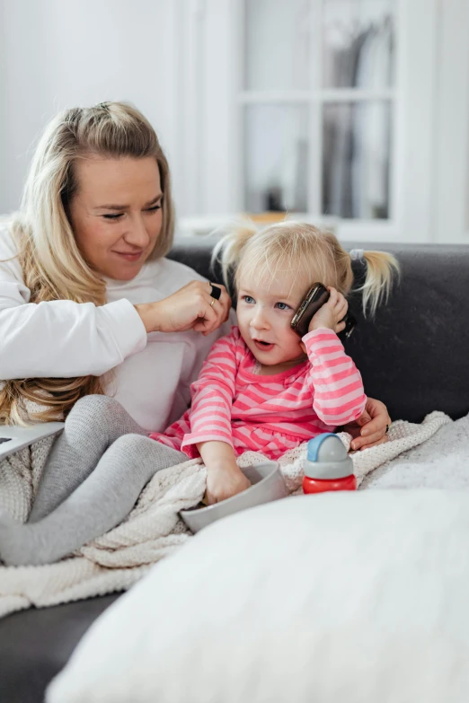 a woman combing a little girl's hair while sitting on a couch, girl making a phone call, square, screensaver, 1x