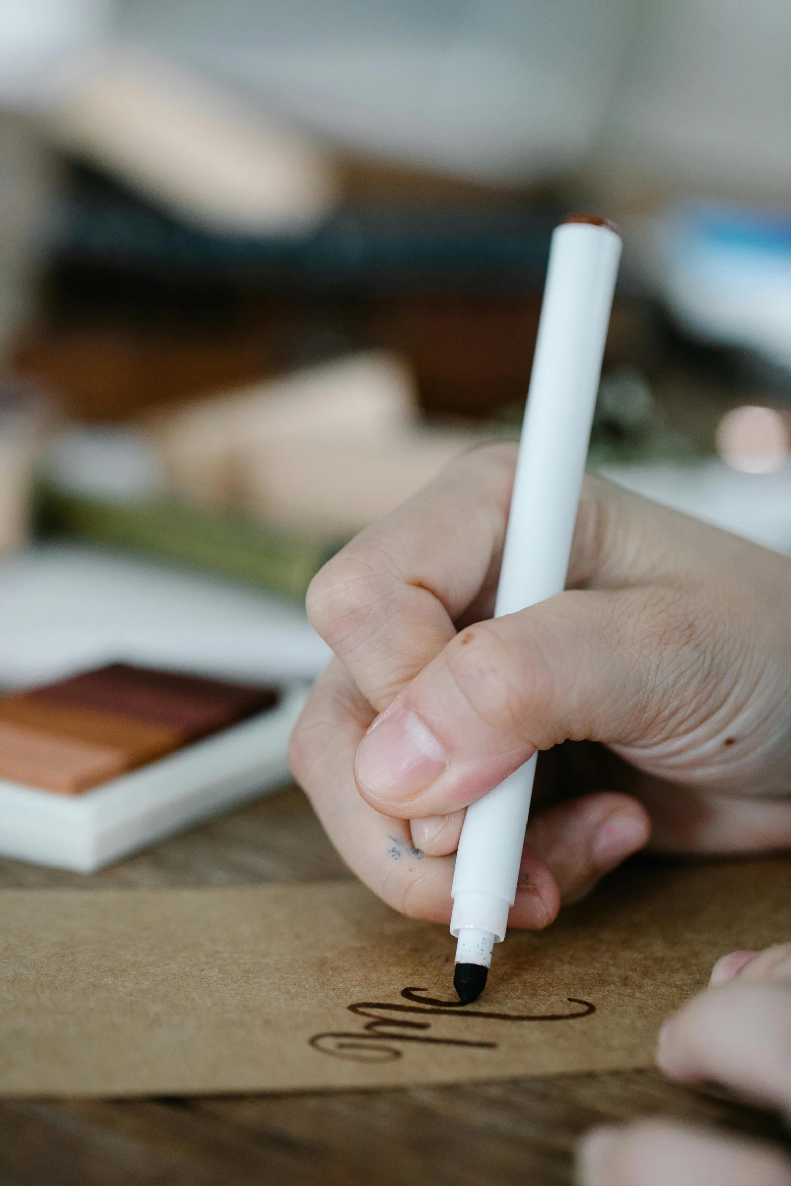 a close up of a person writing on a piece of paper, brown and white color scheme, chartpak ad markers, crafts and souvenirs, thumbnail