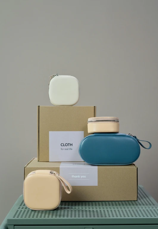 a stack of boxes sitting on top of a table, pouches, cream and blue color scheme, airpods, 3 colours