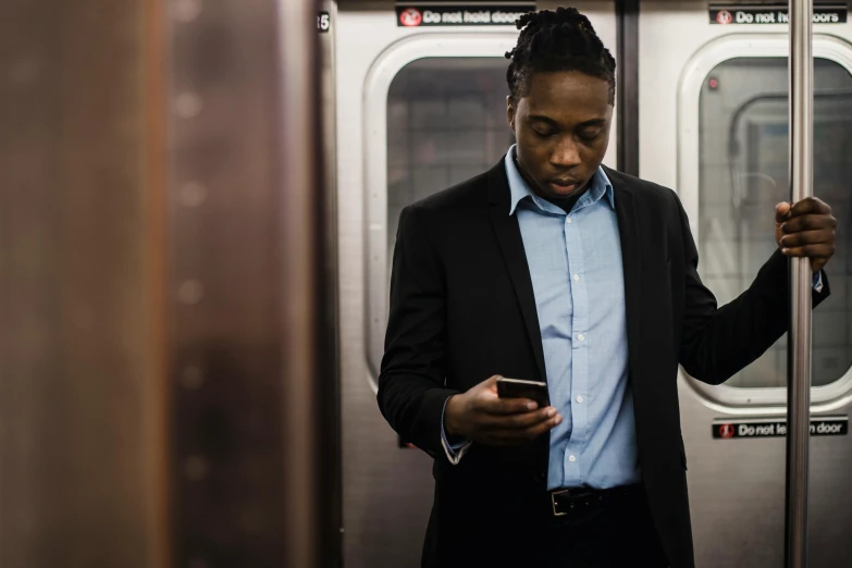 a man standing on a subway looking at his cell phone, pexels contest winner, renaissance, mkbhd, a man wearing a black jacket, integrating with technology, ignant