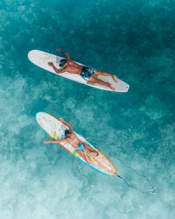 a couple of people riding surfboards on top of a body of water, flatlay, clear blue water, thumbnail, single subject