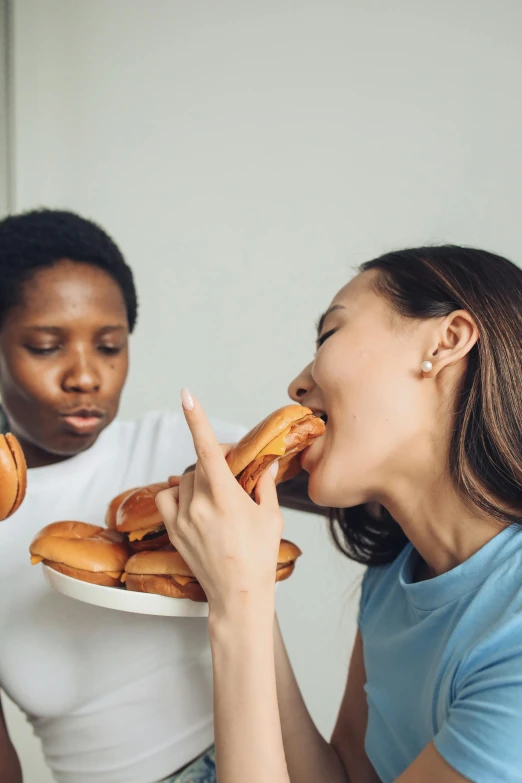 two women sitting at a table eating donuts, by Nina Hamnett, shutterstock contest winner, sausages, kissing each other, crispy buns, masculinity