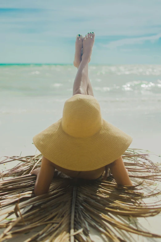 a person laying on top of a palm leaf covered beach, wearing wide sunhat, legs intertwined, light tan, pro - vida