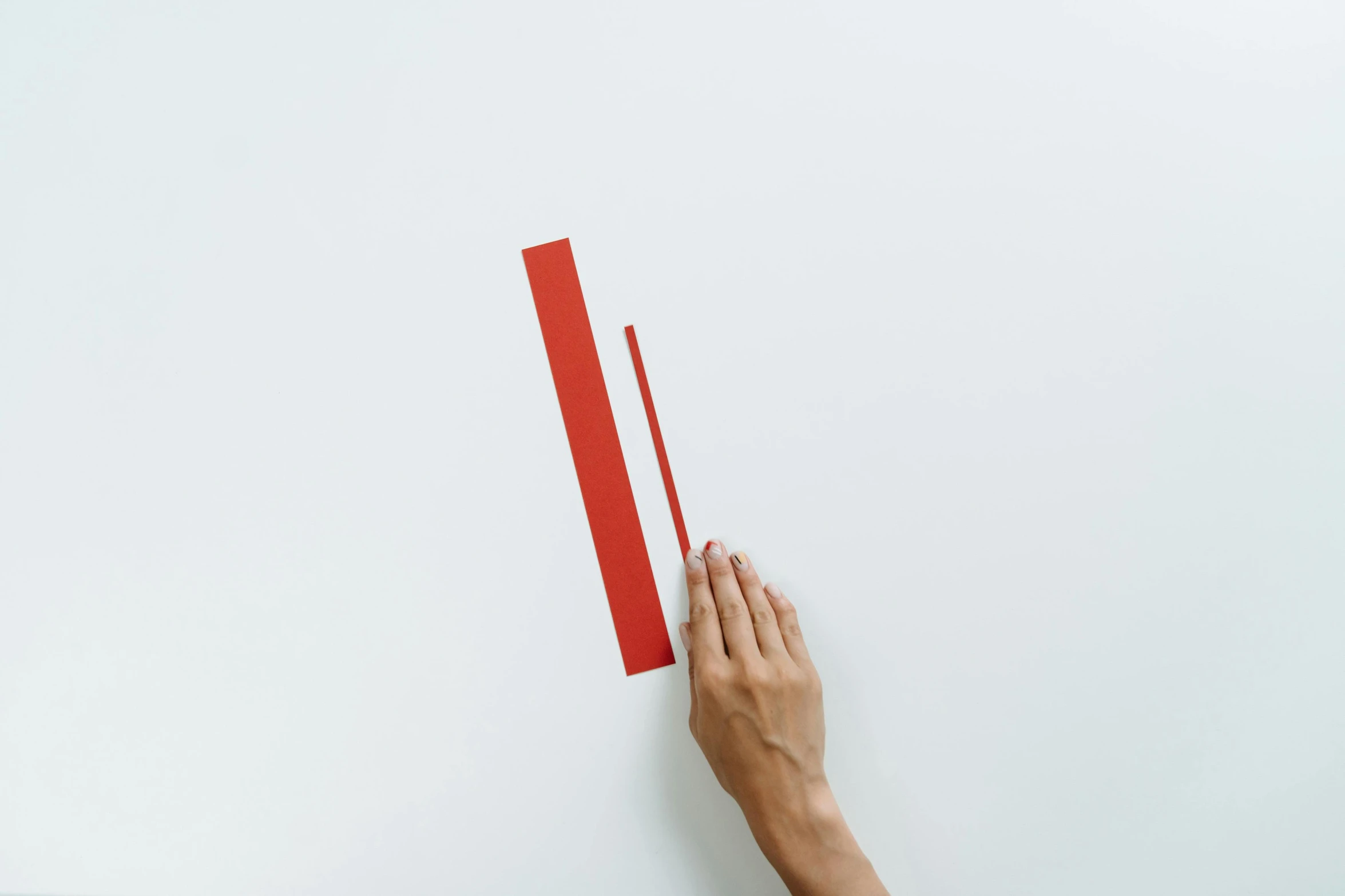 a person's hand holding a red piece of paper, inspired by Barnett Newman, postminimalism, single long stick, ignant, paper craft, red painted metal