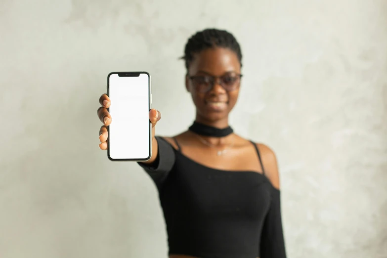 a close up of a person holding a cell phone, black girl, in front of white back drop, posing for a picture, mobile learning app prototype