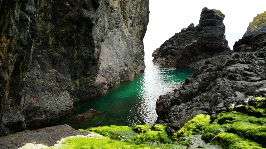 a body of water that is next to some rocks, inspired by Hallsteinn Sigurðsson, unsplash, les nabis, green slime, natural cave wall, pembrokeshire, devils horns