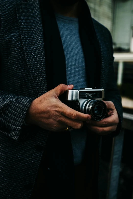 a man holding a camera in his hands, pexels contest winner, well - dressed, hasselblad quality, vintage soft grainy, medium format color photography