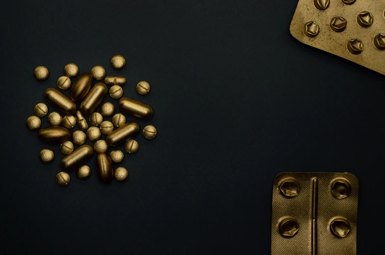 gold pills and capsules on a black background, an album cover, by Emma Andijewska, unsplash, digital art, brass plated, rivets, kris kuksi, medical supplies
