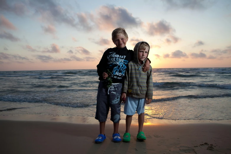 a couple of kids standing on top of a sandy beach, a portrait, by Michael Goldberg, pexels contest winner, israel, avatar image, late summer evening, with a twin