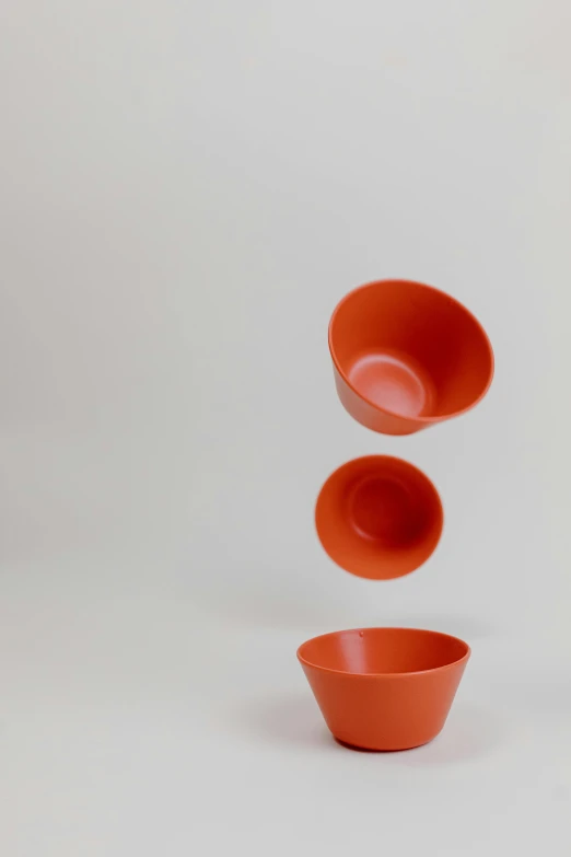 a red bowl sitting on top of a white table, unsplash, conceptual art, floating in mid - air, orange, wood cups, 3/4 view from below