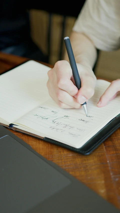 a person writing in a notebook with a pen, thumbnail, background image, large)}], product shot