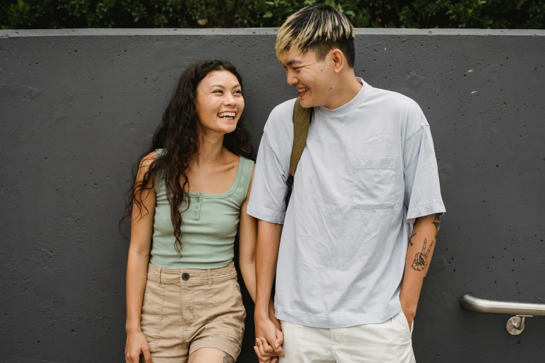 a man and a woman standing next to each other, trending on pexels, half asian, wearing ragged clothing, smiling at each other, ad image