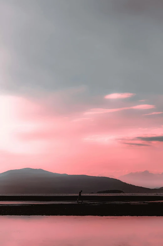 a person standing on a beach next to a body of water, by Alexis Grimou, unsplash contest winner, romanticism, pink storm clouds, distant mountains lights photo, scotland, silhouette of a man