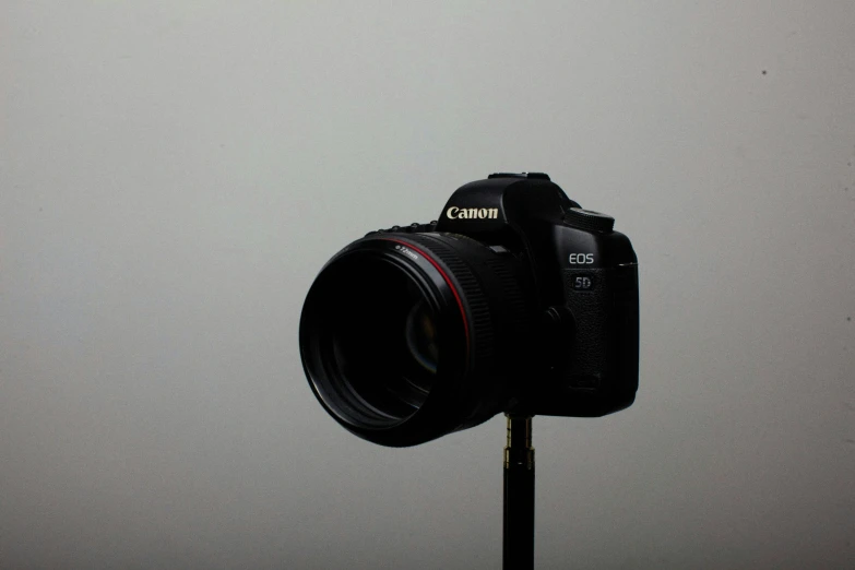a close up of a camera on a tripod, by Gavin Hamilton, canon eos 5d mark 2, set against a white background, camera flash on, modern minimalist f 2 0 clean