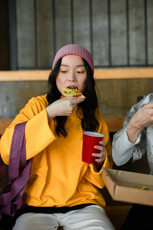 two women sitting on a bench eating food, a portrait, unsplash, renaissance, wearing a yellow hoodie, asian female, ninja turtle eating pizza, movie filmstill