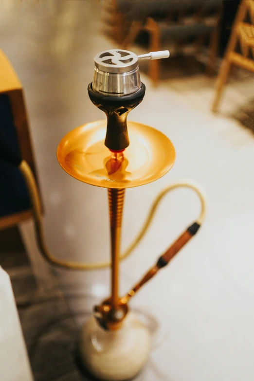 a hooket sitting on top of a table next to a chair, by Matthias Stom, trending on unsplash, hurufiyya, a hookah smoking caterpillar, gold light, detailed product image, floor lamps