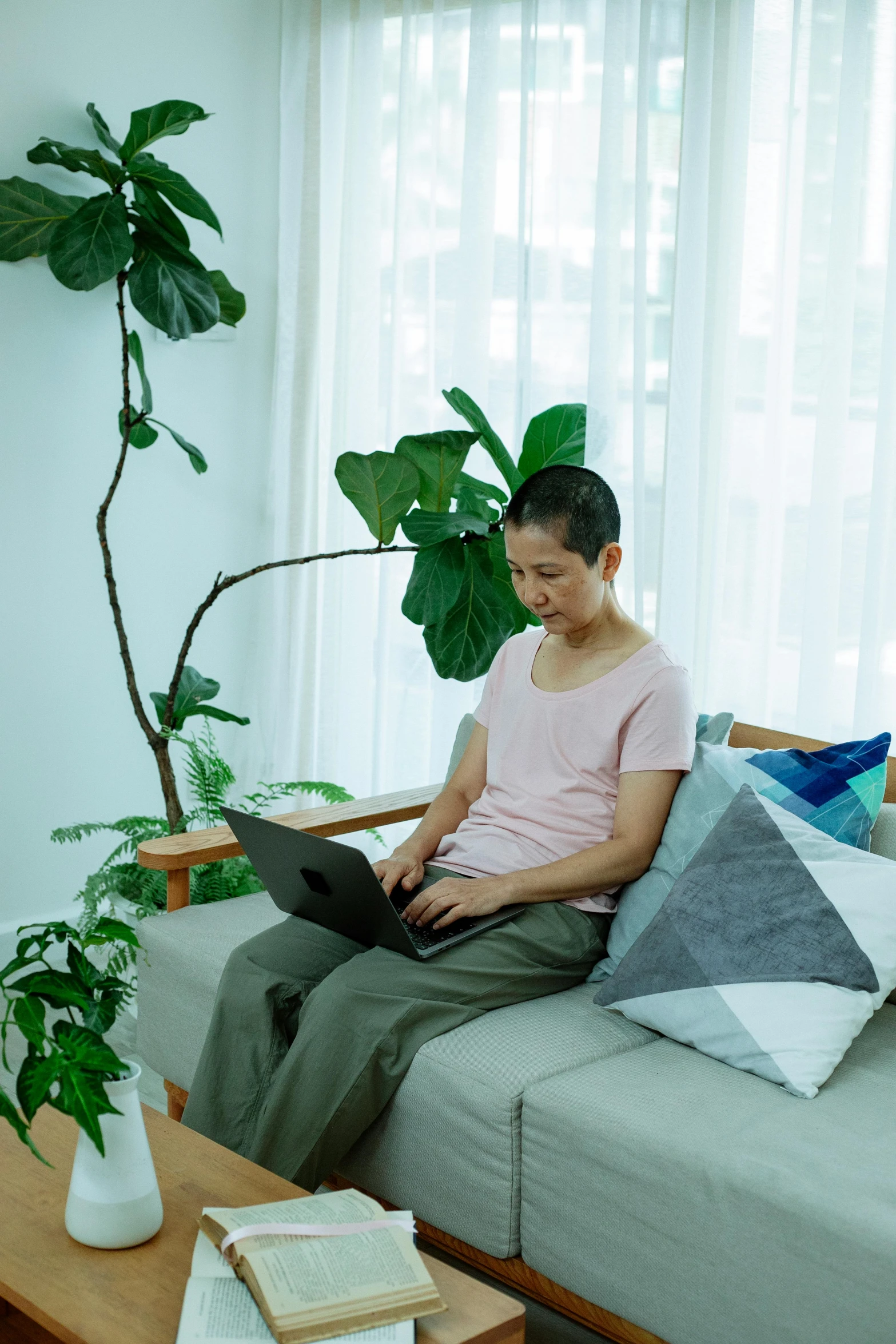 a woman sitting on a couch using a laptop, inspired by Ruth Jên, happening, asian male, plants, profile image, maintenance