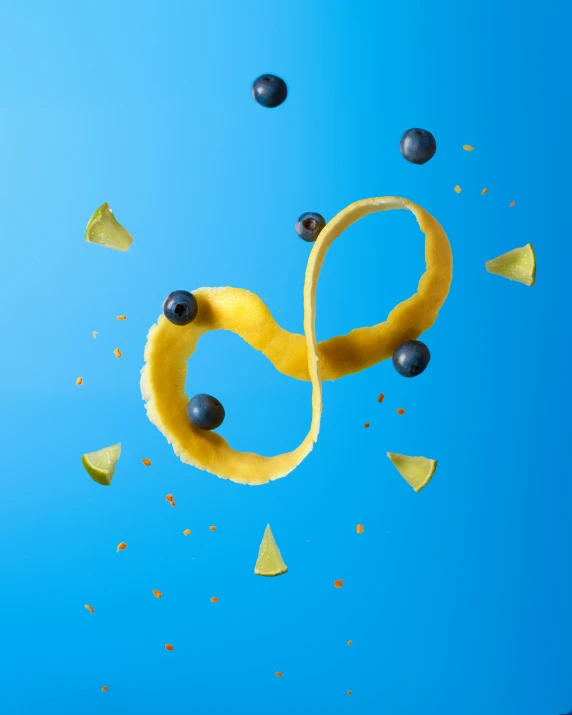 a banana and blueberries are flying in the air, by Alison Geissler, trending on pexels, process art, infinity symbol, behance lemanoosh, yellow and blue ribbons, 8k octan advertising photo