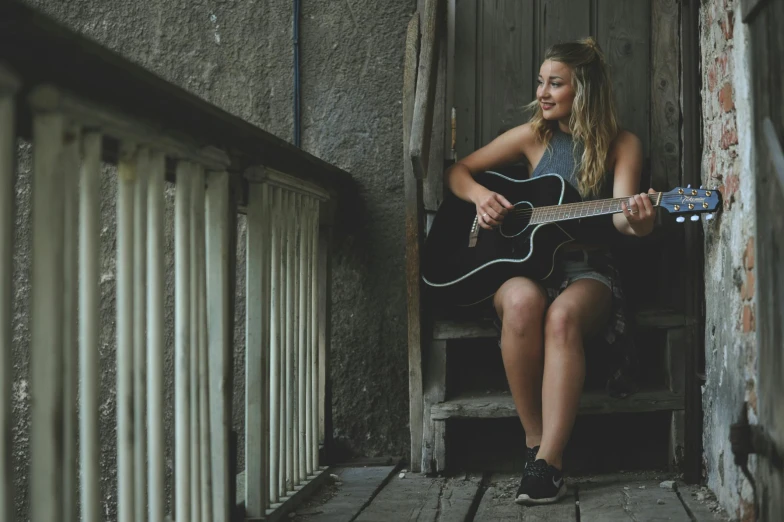 a woman sitting on a porch playing a guitar, a portrait, pexels contest winner, happening, sydney sweeney, 15081959 21121991 01012000 4k, concert, happy girl