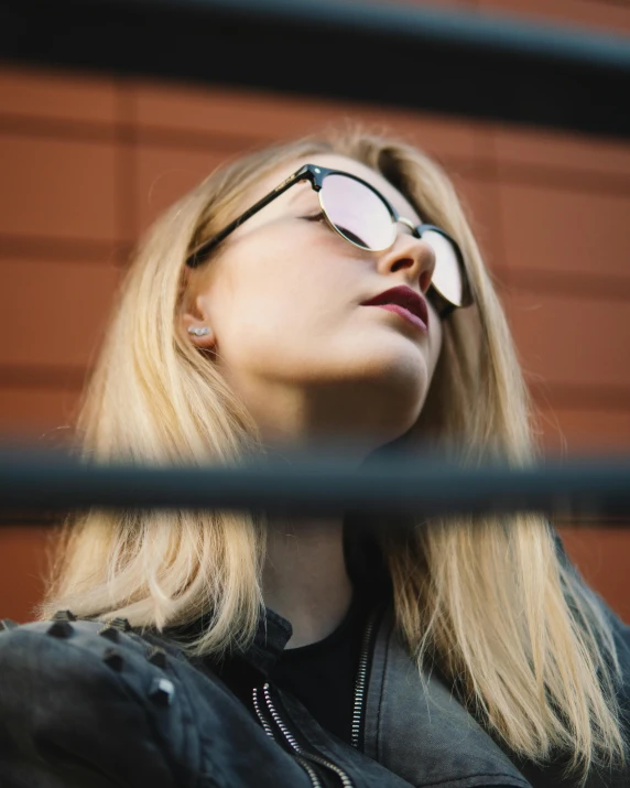 a woman with glasses looking out of a window, inspired by Elsa Bleda, trending on pexels, standing astride a gate, portrait of kim petras, implanted sunglasses, nonbinary model