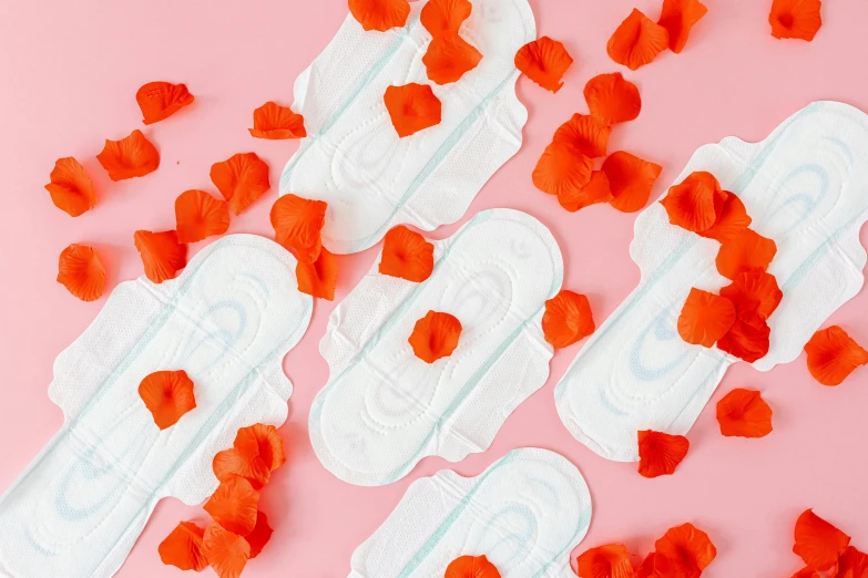 a bunch of sanitary pads sitting on top of a pink surface, by Julia Pishtar, red neon roses, orange and white color scheme, long petals, product design shot