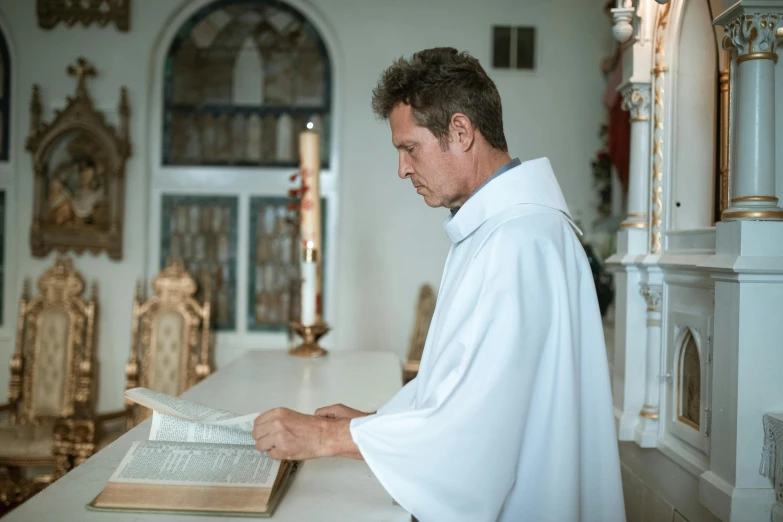 a man reading a book in a church, a photo, white robe, profile image, thumbnail