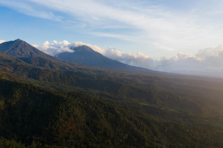 a view of a mountain range with trees in the foreground, unsplash contest winner, sumatraism, infographic of active volcanoes, bali, wide high angle view, late afternoon light