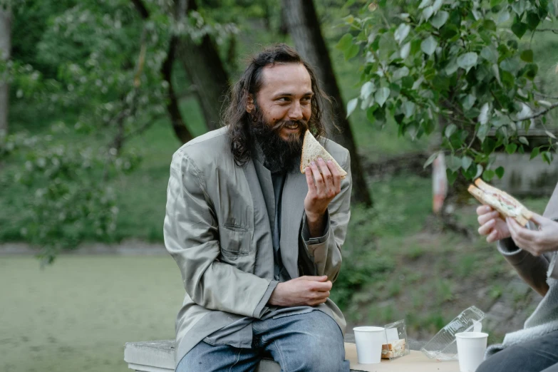 two men sitting at a picnic table eating sandwiches, an album cover, by Attila Meszlenyi, pexels contest winner, portrait of alan watts, orthodox, smiling man, ilya golitsyn