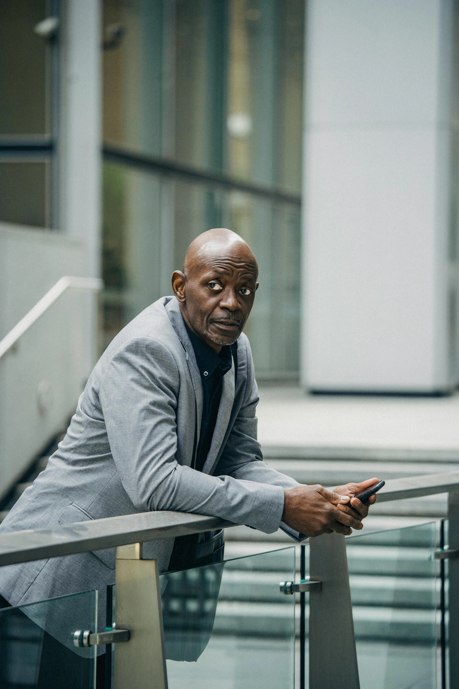 a man leaning on a railing looking at his cell phone, inspired by Robert Bain, lance reddick, norman foster, press shot, victor ngai