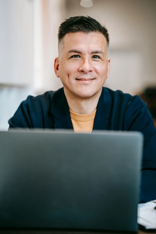 a man sitting in front of a laptop computer, a photo, inspired by Carlos Berlanga, trending on pexels, lovingly looking at camera, jeremy pitkin, subject is smiling, lgbtq