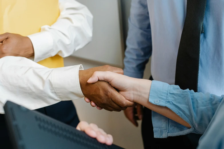 a group of people shaking hands in front of a computer, colour corrected, thumbnail, diverse, alana fletcher