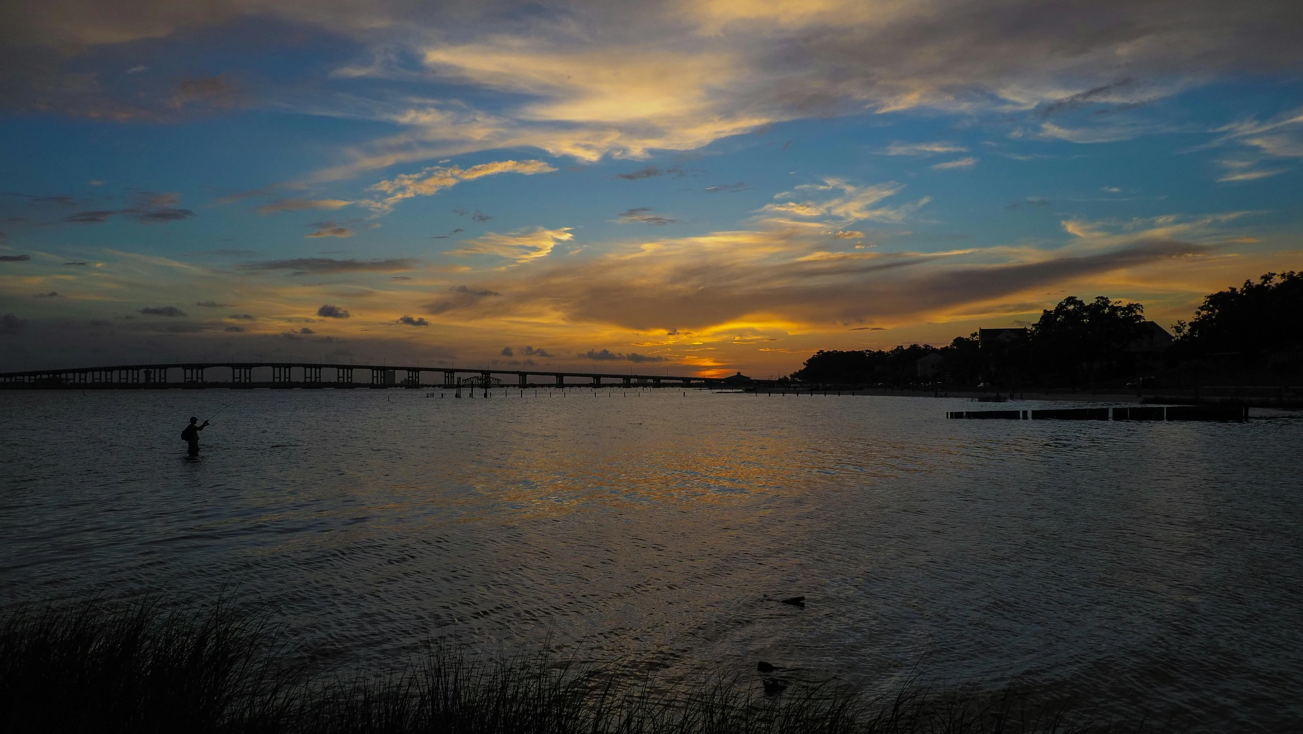 a sunset over a body of water with a bridge in the distance, profile image