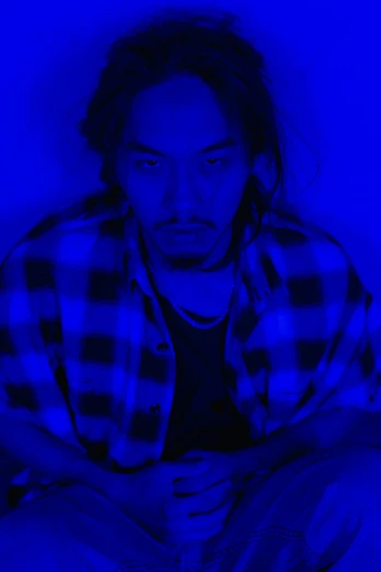 a man sitting on top of a bed under a blue light, inspired by Zhu Da, headshot, frank dillane, gif, yohji yamamoto