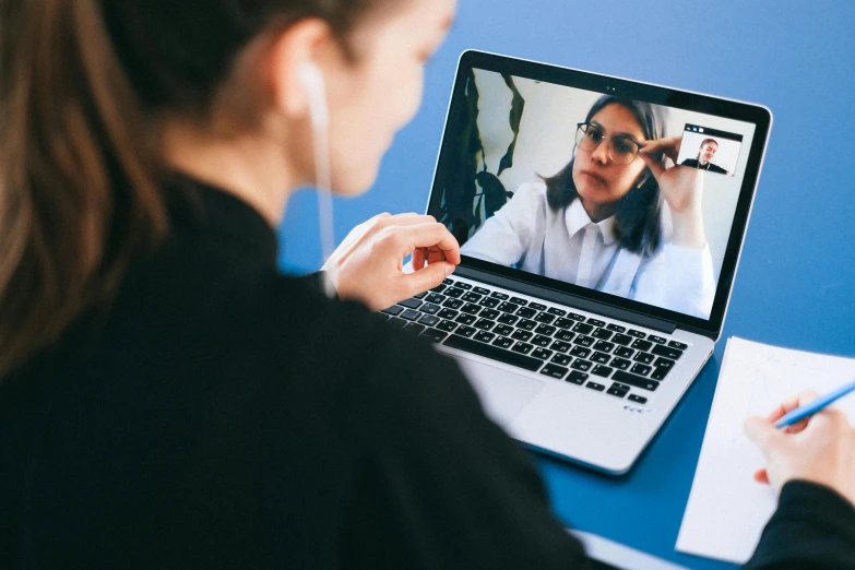 a woman sitting in front of a laptop on a desk, trending on pexels, video art, wearing headset, close up to the screen, giving an interview, instagram picture