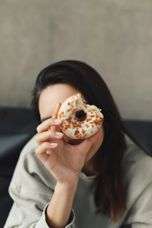 a woman holding a donut in front of her face, a picture, inspired by Elsa Bleda, trending on pexels, square, made of glazed, white, caramel