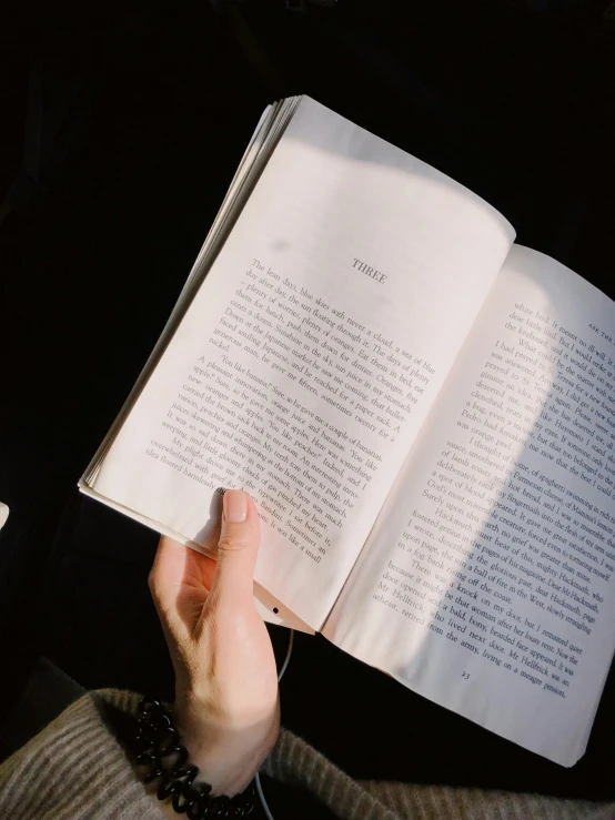 a person reading a book next to a cup of coffee, by Grace Polit, trending on unsplash, happening, seen from below, translucent white skin, instagram story, holding a stuff