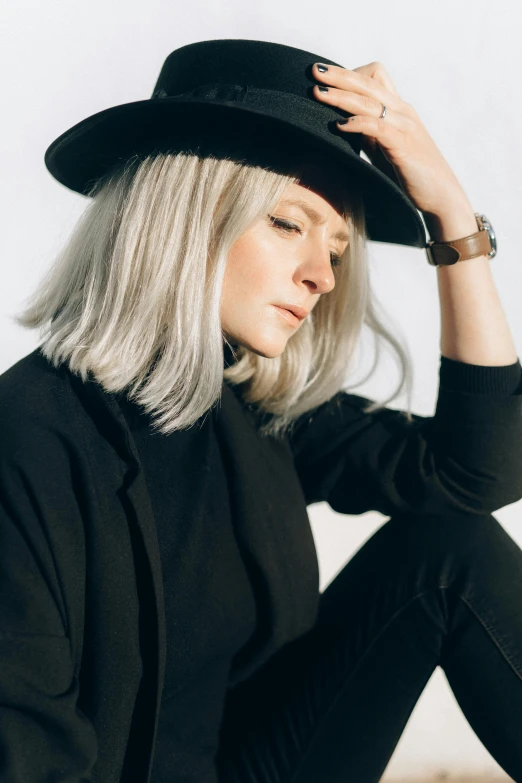 a woman sitting on the ground wearing a black hat, an album cover, trending on pexels, white - blond hair, profile portrait, silver，ivory, jovana rikalo