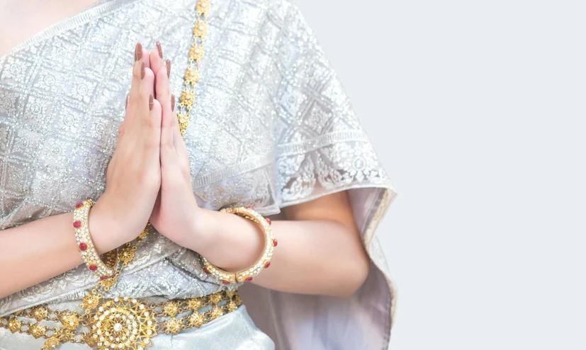 a close up of a woman in a sari, trending on unsplash, cloisonnism, prayer hands, background image, wearing long silver robes, parody work