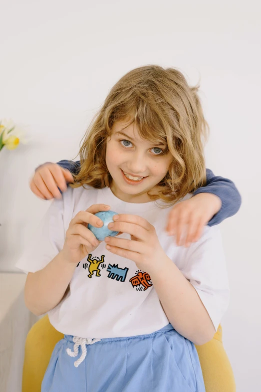 a couple of young girls standing next to each other, inspired by Sarah Lucas, trending on reddit, tamagotchi, on a white table, dressed in a white t shirt, official product photo