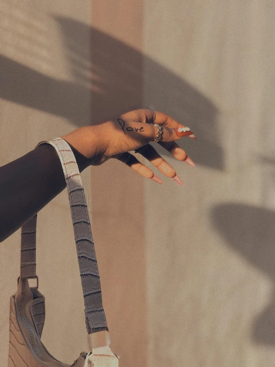 a woman holding a purse and a cell phone, an album cover, inspired by Elsa Bleda, trending on pexels, visual art, long fingernails, sun and shadow, grey skin, dark skinned