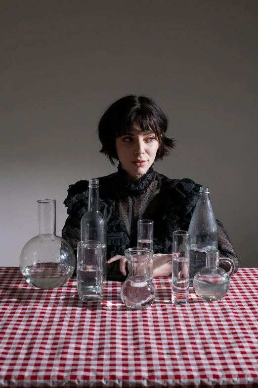 a woman sitting at a table with a red and white checkered table cloth, an album cover, inspired by Cindy Sherman, unsplash, hyperrealism, vases and bottles, finn wolfhard, tansparent water, scientific glassware